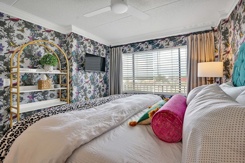 master bedroom with gold accents and patterned wallpaper 